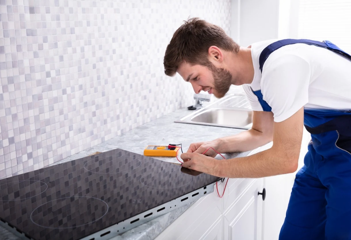 Technician checking an electric cooktop with a multimeter