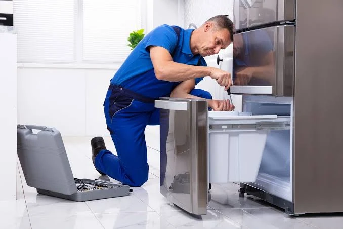 Technician inspecting the freezer drawer of a stainless steel refrigerator