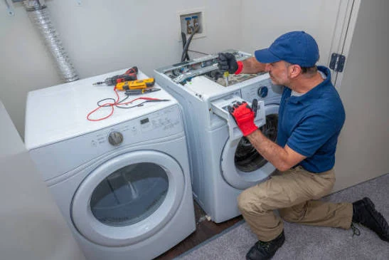 Technician inspecting an open washing machine beside a dryer